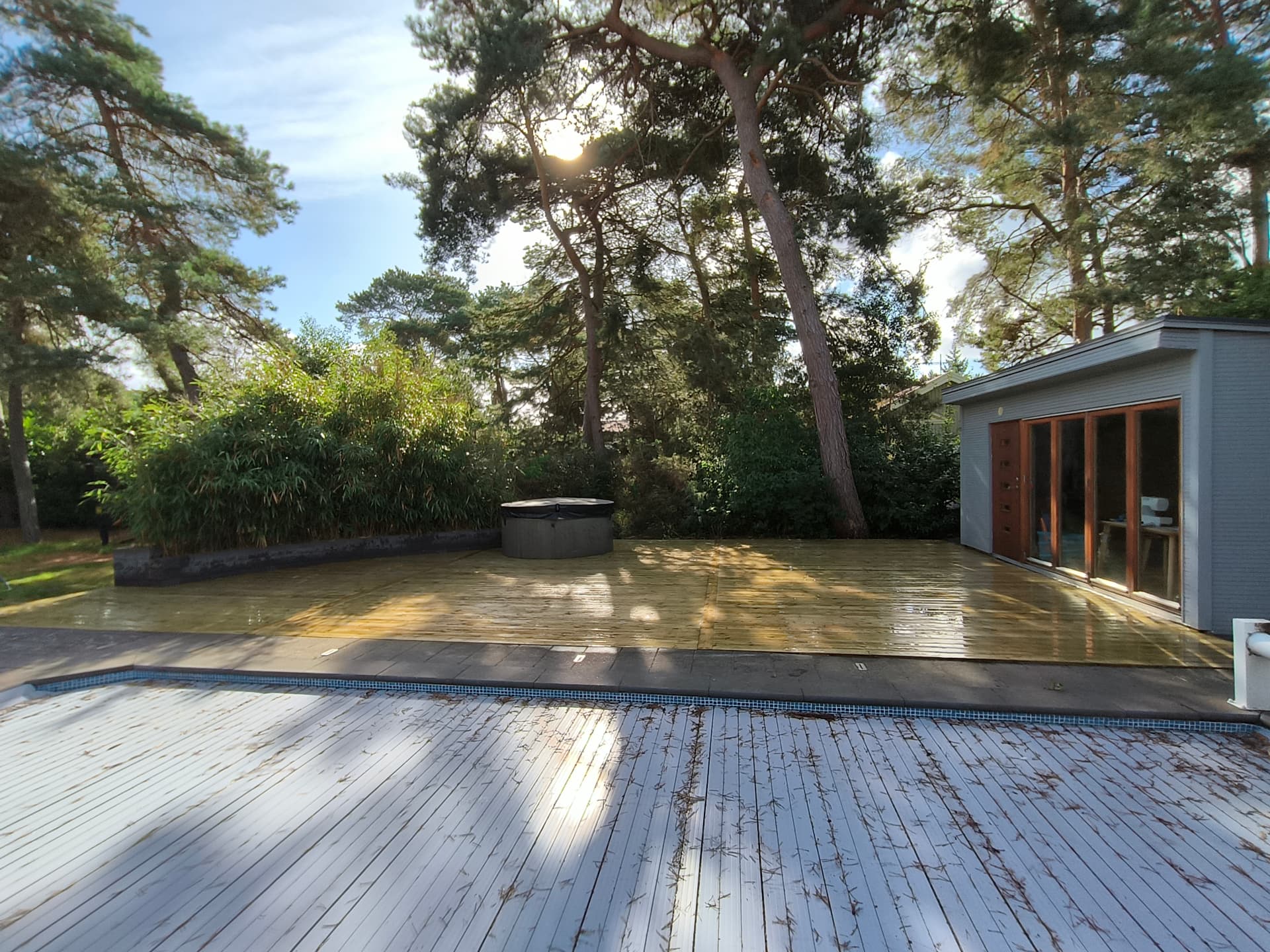 Trädgård med trädäck, pool och bambuhäck efter anläggning av BT-Service